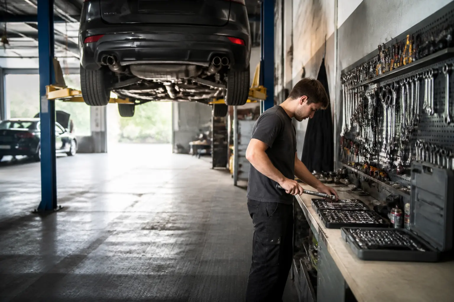 Garage libre service pour réparer soi-même : voiture sur pont, outils pro et atelier partagé lumineux.